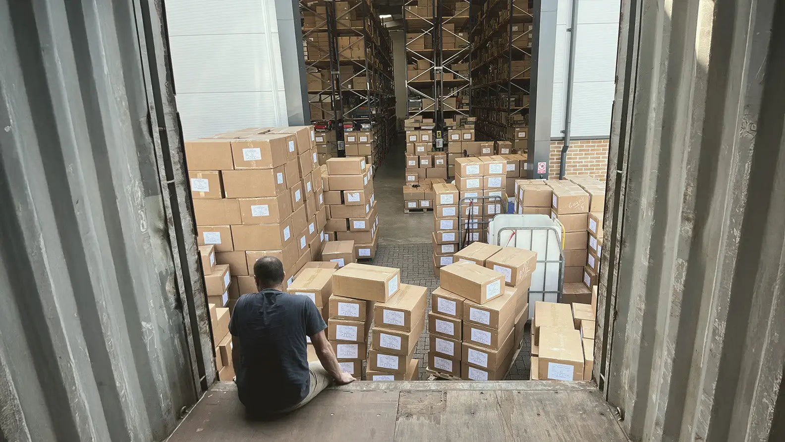 Man inside shipping container with boxes showcasing NewForest Clothing SS25 collection for country hunting gear