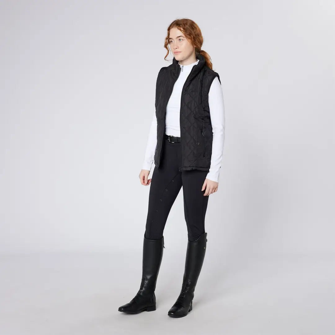 Woman wearing Cameo Performance Tights in black vest, pants, and boots for performance riding