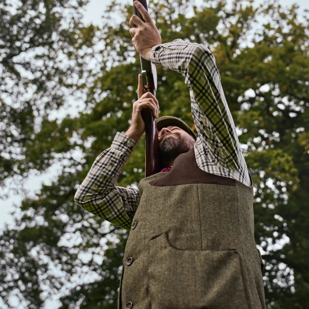 Man holding shotgun wearing Harkila Kenmore Shooting Waistcoat for outdoor shooting