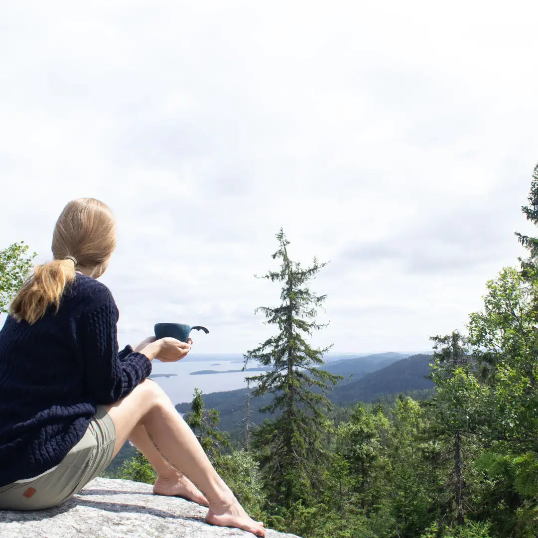 Woman enjoying a Kupilka Large Cup while overlooking a stunning scenic landscape