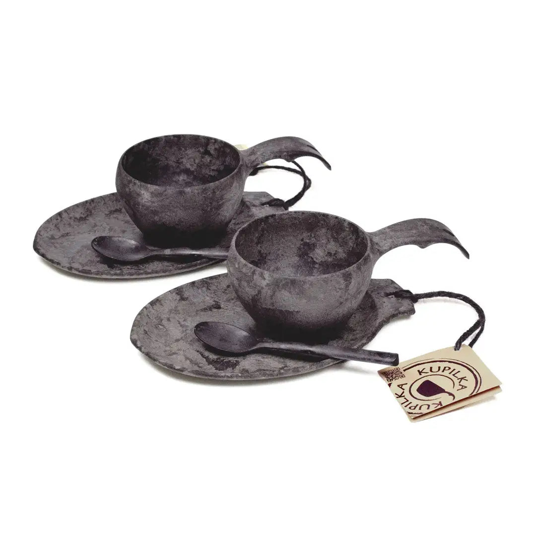 Two dark gray cup and saucer sets with spoons in the Kupilka Slow Down Gift Set