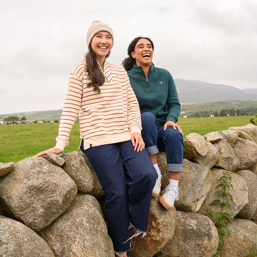 Two women in casual wear sitting on a stone wall, showcasing Lighthouse Ladies Coral Jersey