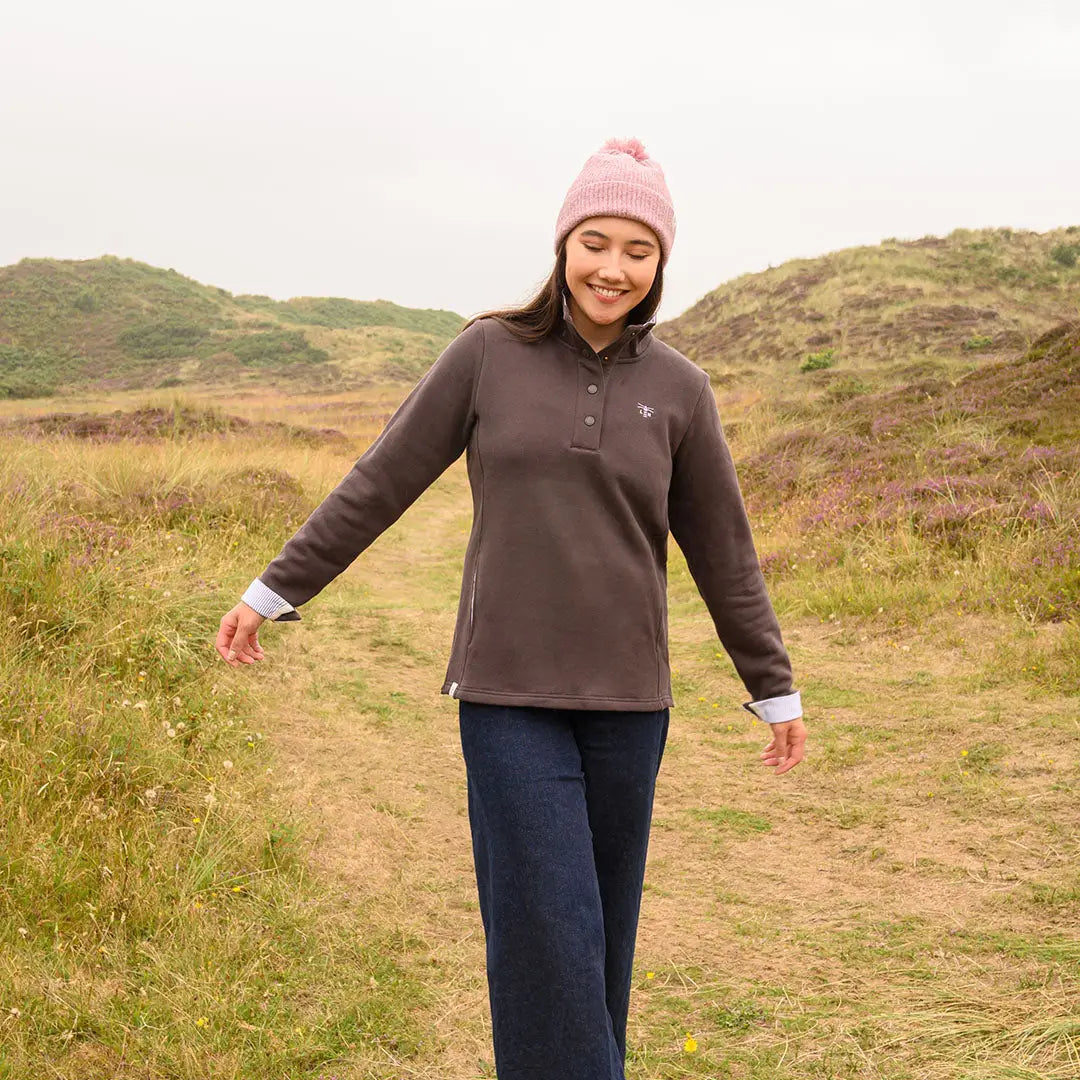 Woman in brown polo, dark jeans, pink beanie wearing Lighthouse Ladies Haven II Jersey