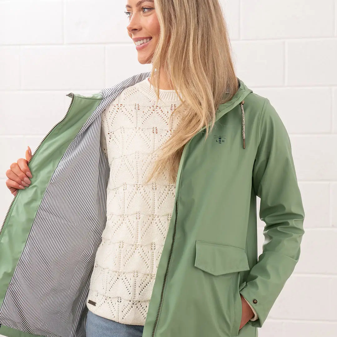 Woman wearing a Lighthouse Ladies Lucy Coat in stylish green, perfect for rainy days