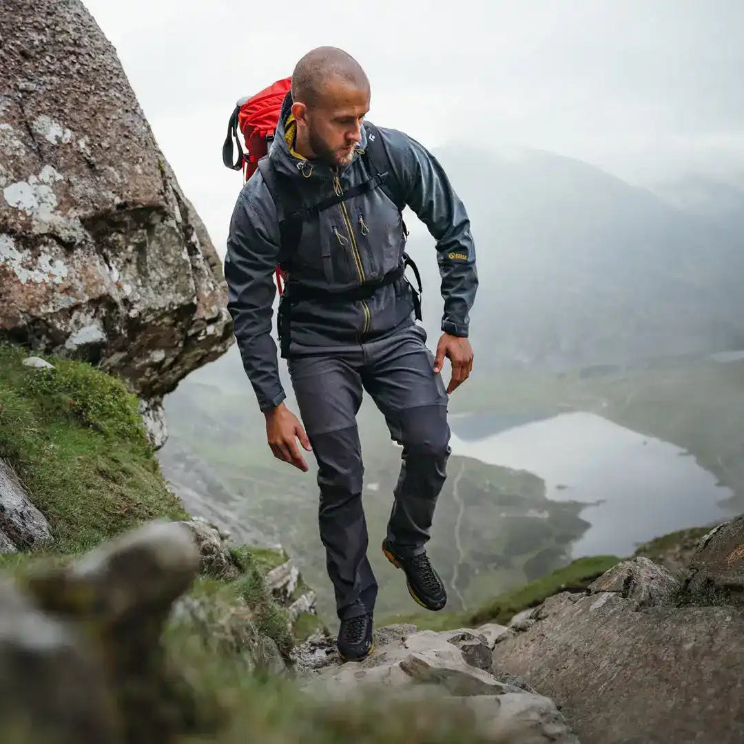 Hiker on misty mountainside wearing Keela Hydron Softshell Jacket navigating rocky terrain
