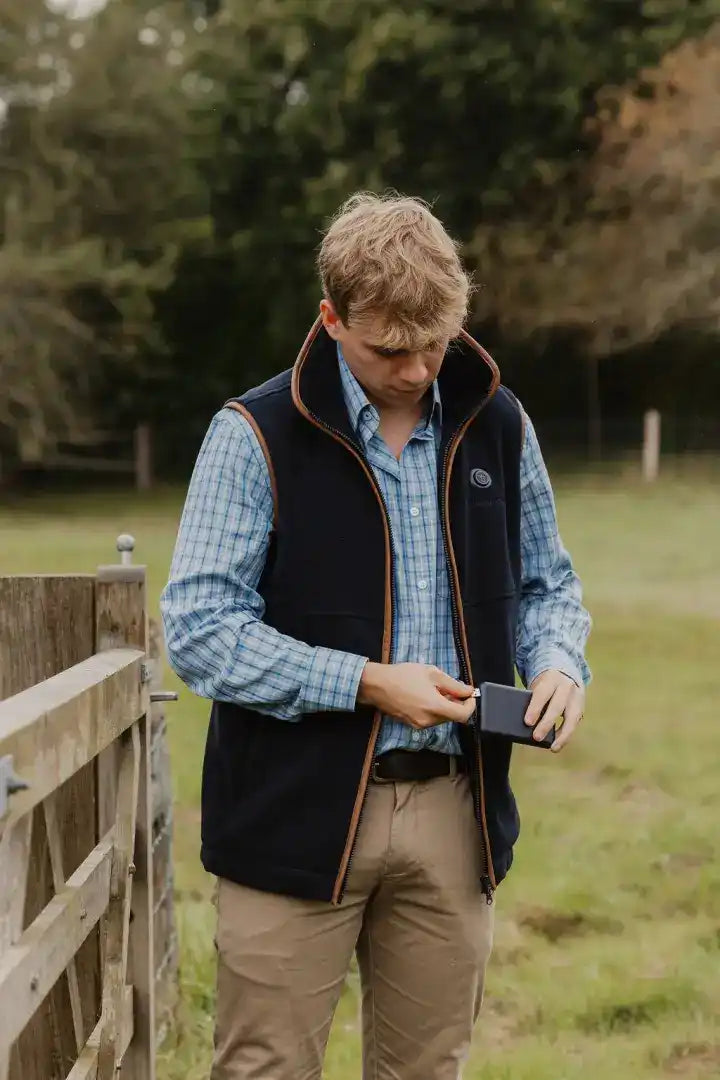 Man in vest holding wallet wearing New Forest Heated Fleece Gilet