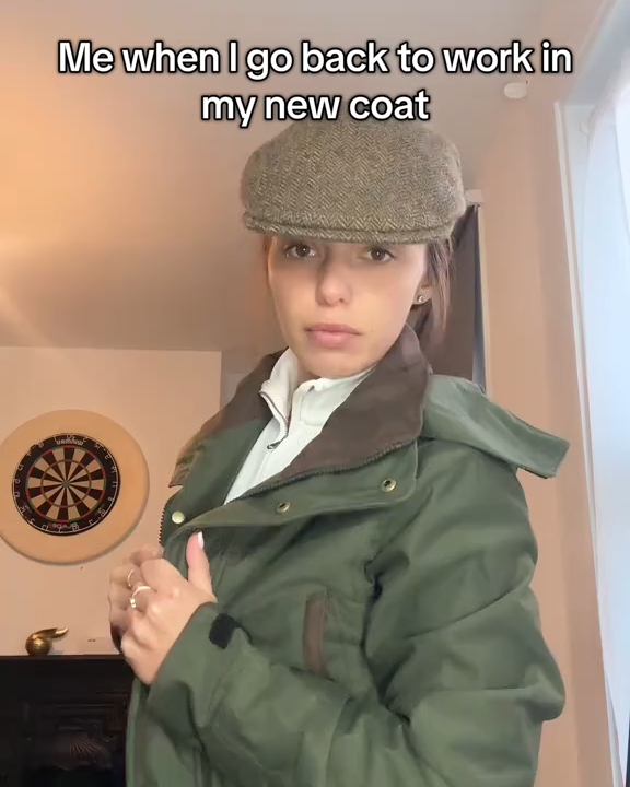Person wearing a green coat and flat cap indoors with text overlay.