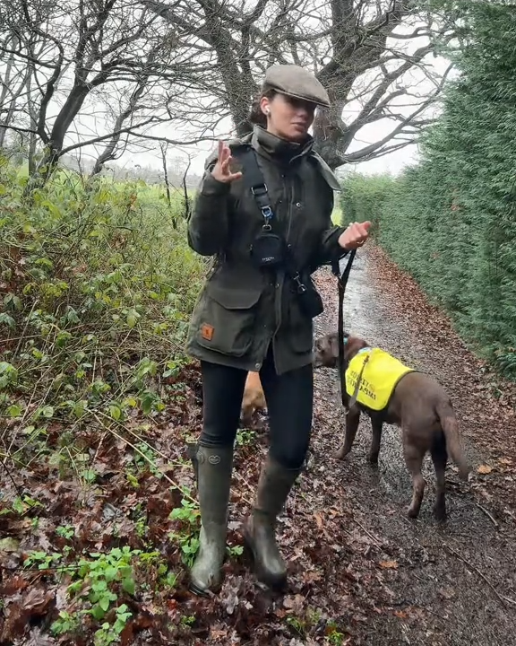 Person in outdoor gear with a dog on a leash in a wooded area