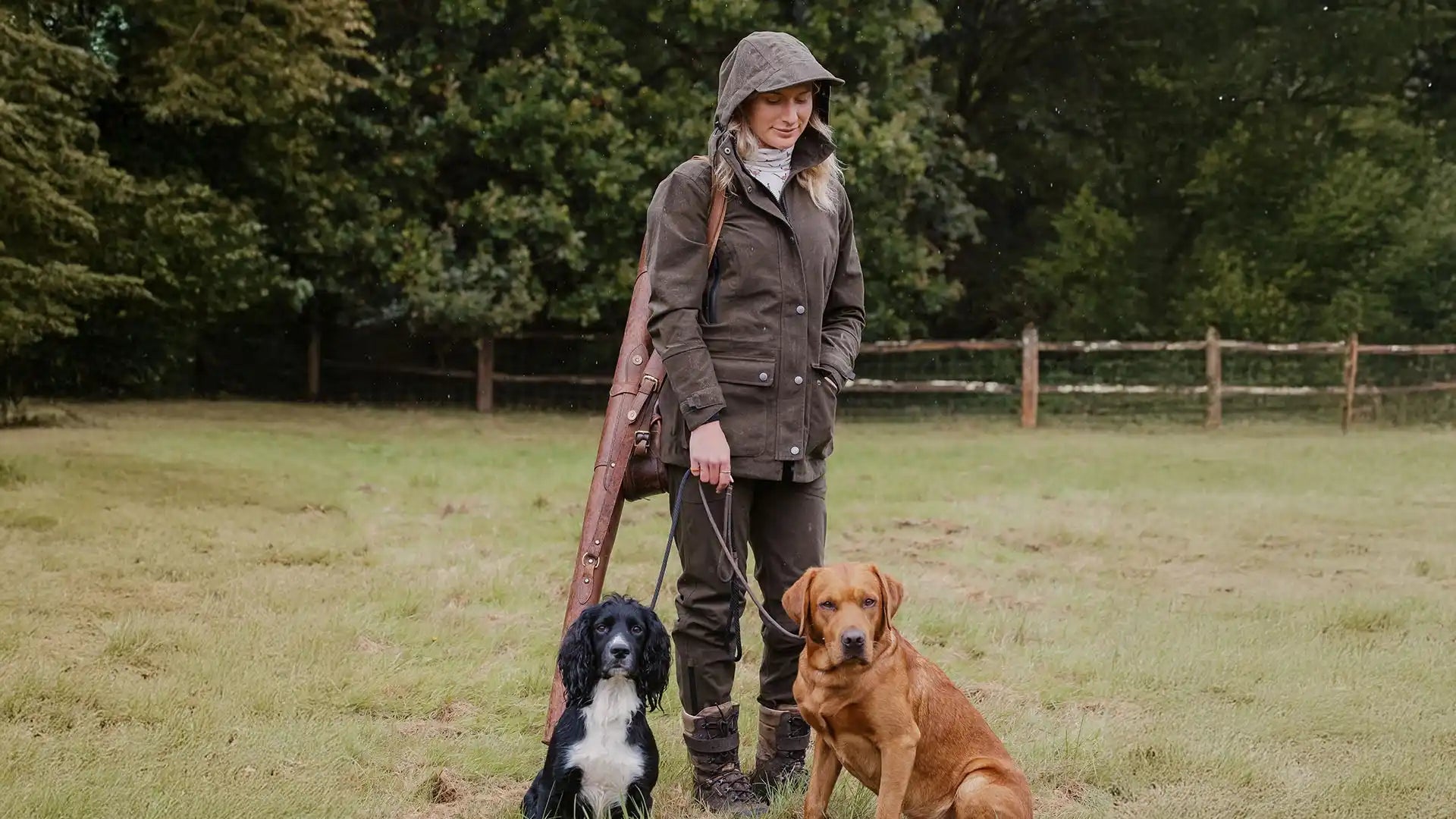 Woman in hunting attire with two dogs.