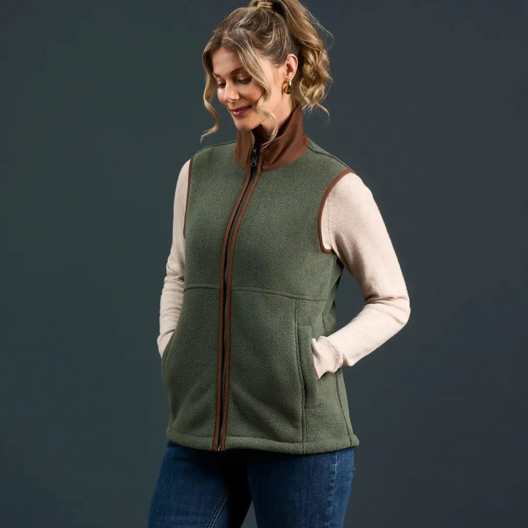 Woman wearing Alan Paine Aylsham Ladies Fleece Gilet in green with brown trim for warmer days
