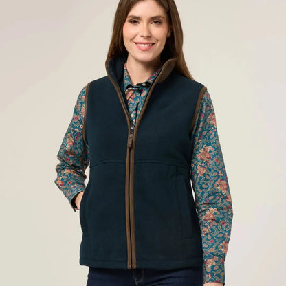 Woman’s teal vest with brown trim over patterned shirt, perfect for warmer days worn