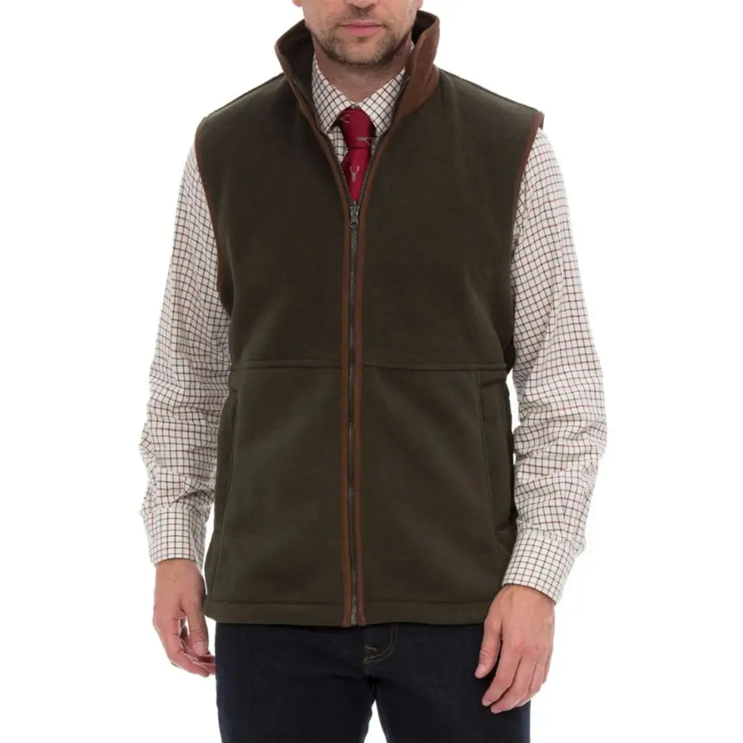 Alan Paine Aylsham men’s dark green fleece vest with brown trim over checkered shirt