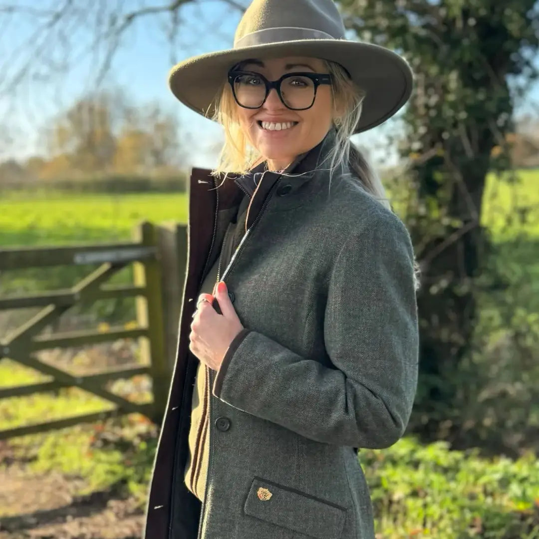 Smiling woman in Alan Paine Combrook waterproof field jacket with green tweed and fedora