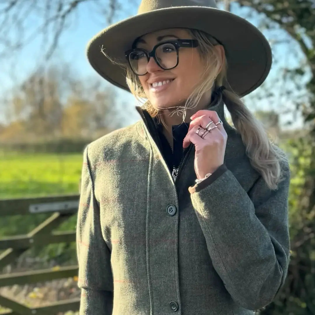 Woman in green tweed jacket and olive fedora showing Alan Paine Combrook waterproof field jacket