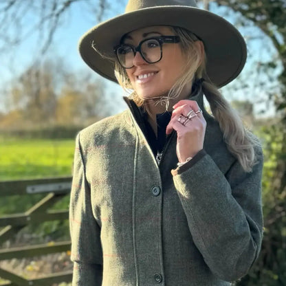 Woman in green tweed jacket and olive fedora showing Alan Paine Combrook waterproof field jacket