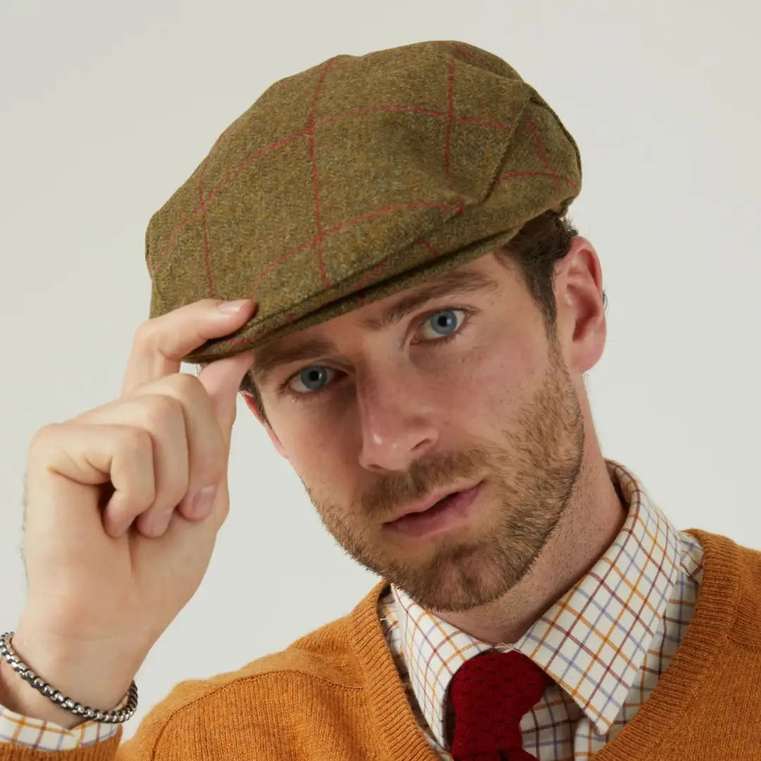 Man wearing Alan Paine Combrook tweed flat cap with red plaid shirt and orange cardigan
