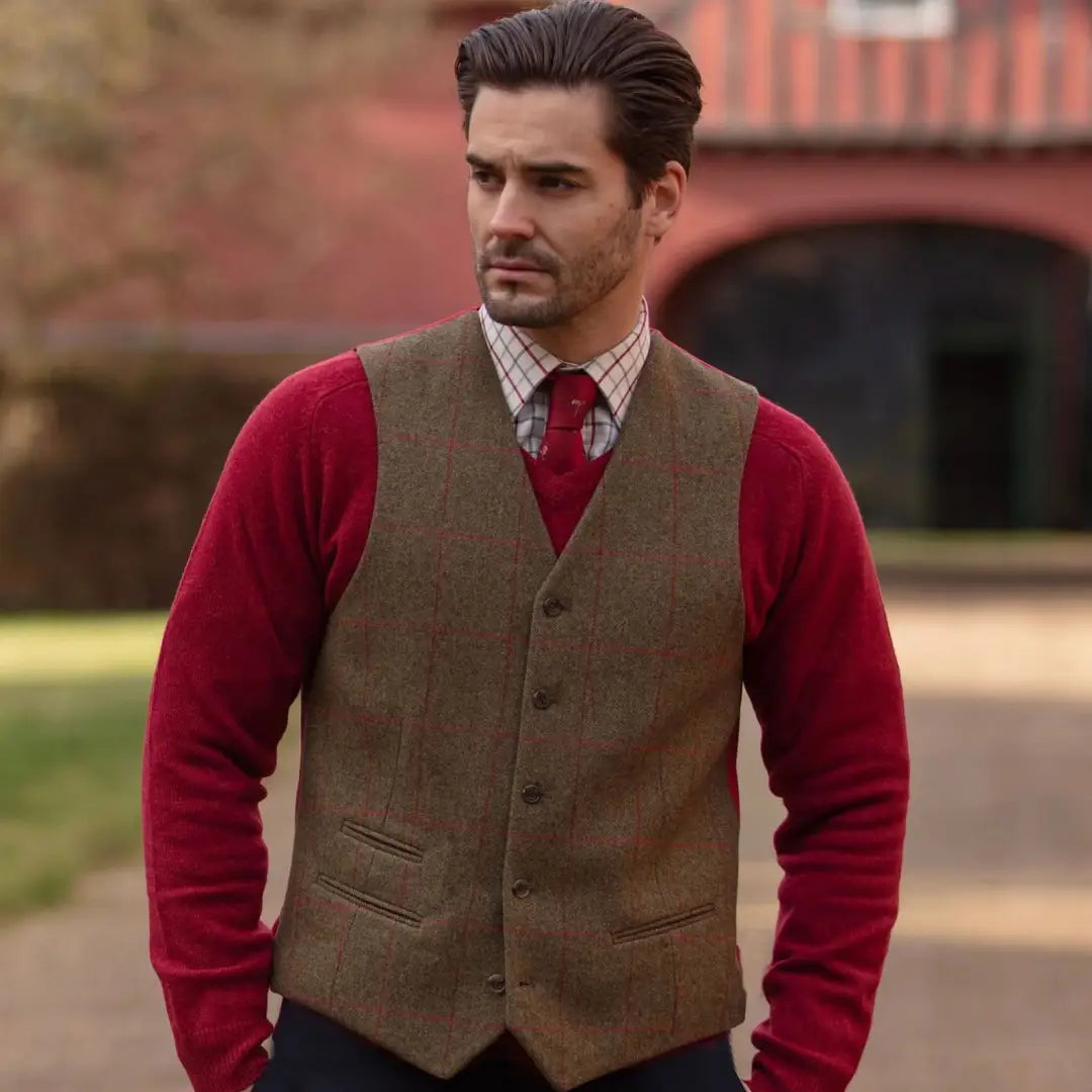 Man wearing Alan Paine’s softest red sweater with a brown tweed vest, action pleat ensures unrestricted style