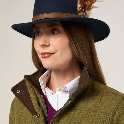 Stylish woman in Alan Paine Rutland tweed waterproof coat with fedora and layered look