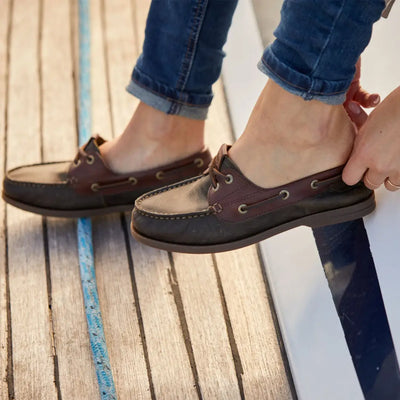 Pair of feet in Ariat Womens Antigua Boat Shoes with rolled-up jeans in a casual setup
