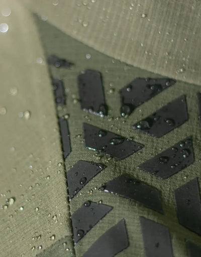 Bushbuck Alpine Waterproof Jacket in water-resistant olive green fabric with black geometric pattern for wet weather country clothing