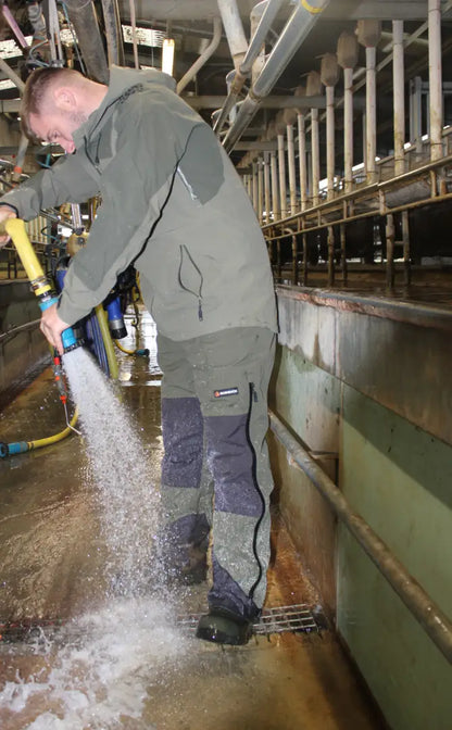 Man spraying water with a hose wearing Bushbuck Defender Waterproof Bib Overtrousers