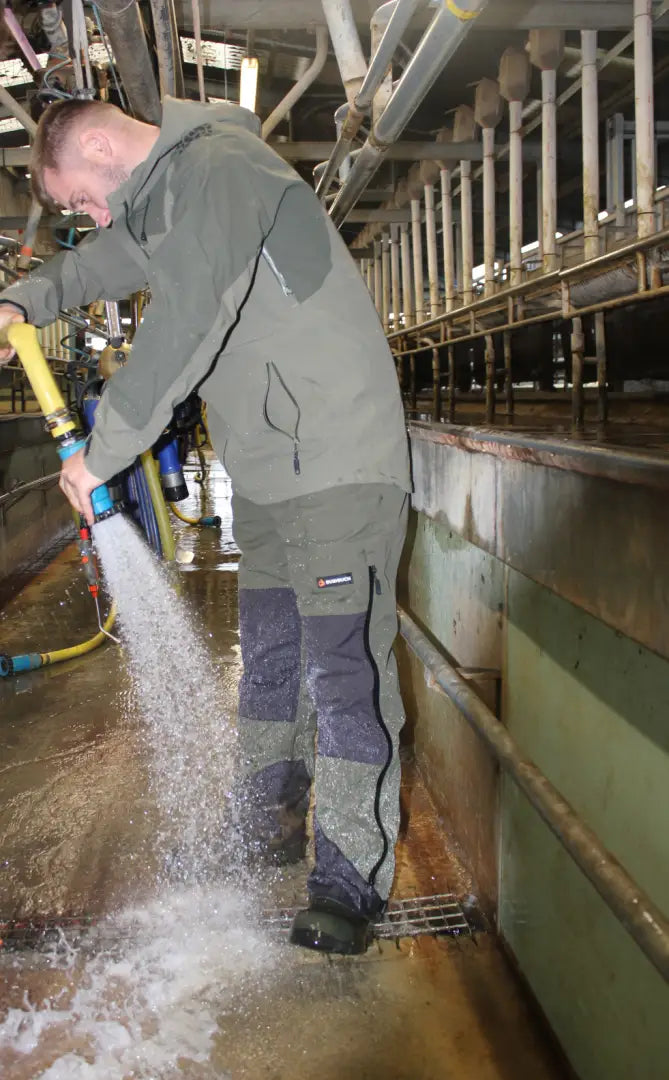 Man spraying water with a hose wearing Bushbuck Defender Waterproof Bib Overtrousers