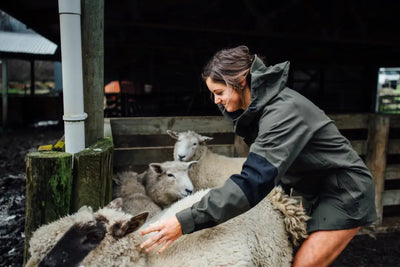 Woman petting sheep in Bushbuck Defender Waterproof Jacket, perfect country clothing for hunting adventures