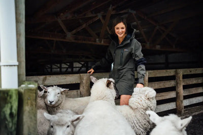 Woman in Bushbuck Defender Waterproof Jacket with sheep, perfect for country clothing and hunting