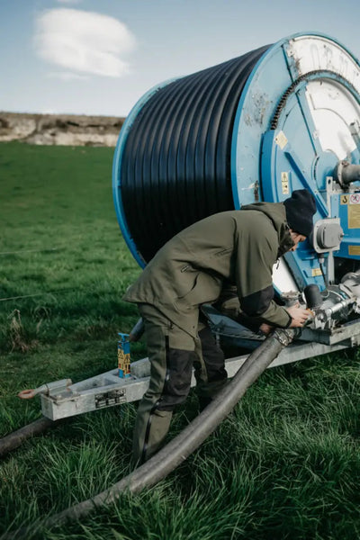 Irrigation reel with worker connecting hose in Bushbuck Defender Waterproof Jacket for hunting