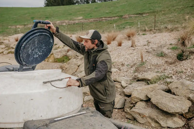 Man opening a white water tank while wearing Bushbuck Frontier Windproof Fleece Pullover for country clothing outdoor gear