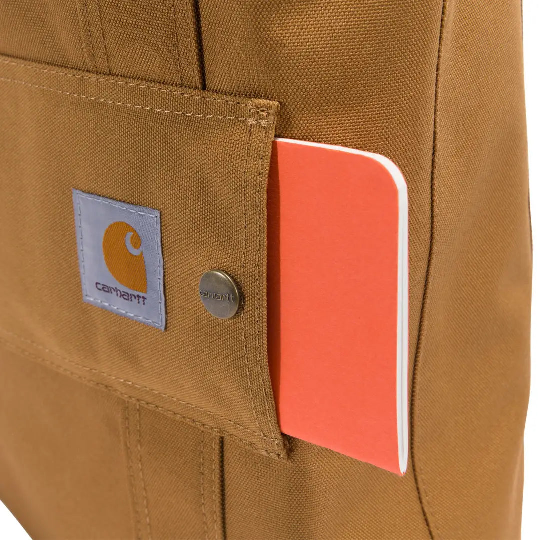Carhartt vertical open tote bag with brown canvas utility pocket and orange notebook