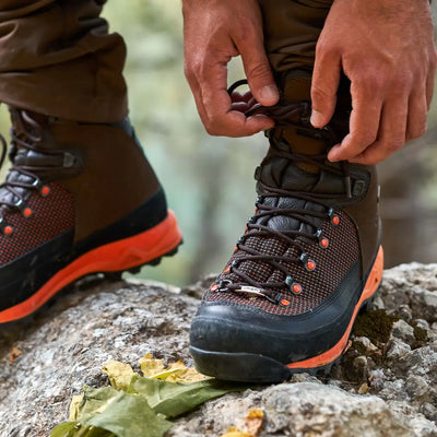 Hiking boot with orange accents laced up on rocky surface for outdoor adventures