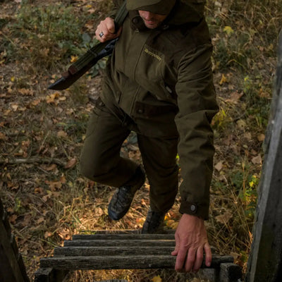 Person in military-style gear climbing wooden steps wearing Deerhunter Eagle Trousers