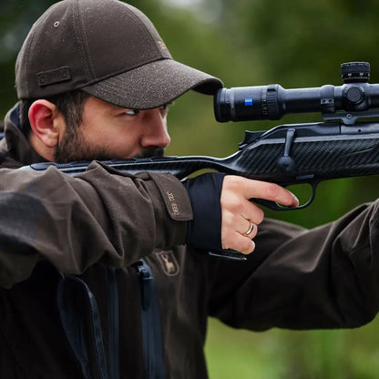 Hunter aiming rifle with scope wearing Deerhunter Game Cap for outdoor adventures