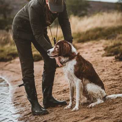 Dog sitting on a dirt path next to a person in Deerhunter Lady Ann Full Stretch Trousers