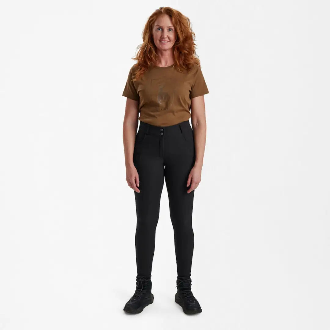 Standing woman in brown t-shirt and black pants wearing Deerhunter Lady Hunting Tights