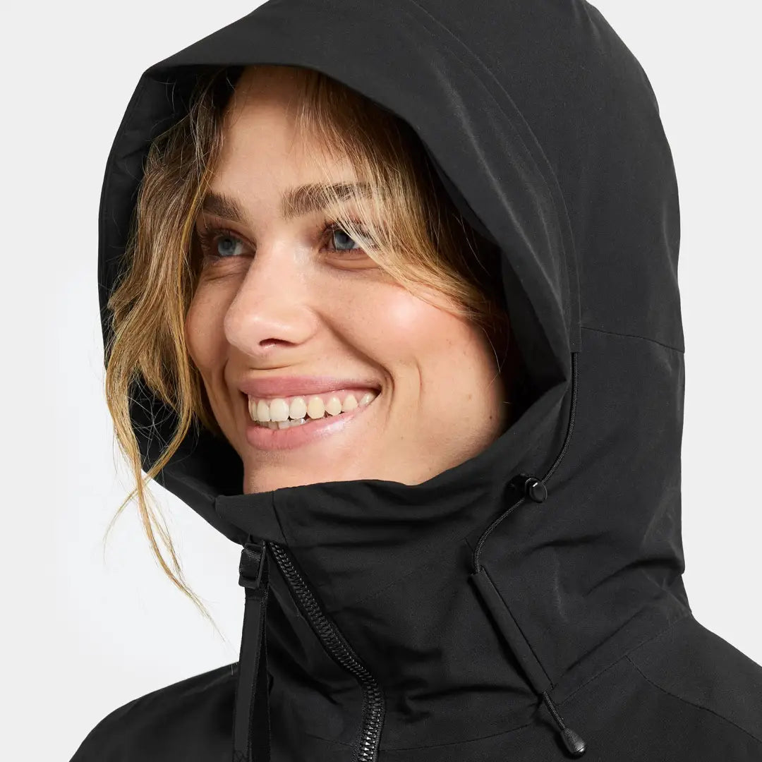 Smiling woman in black hooded jacket from Didriksons Helle Womens Parka for outdoor country clothing