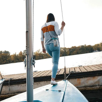 Woman enjoying the sun on a sailboat with a Fidlock Medi Dry Bag for safe storage