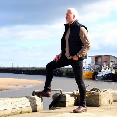 Person in a black vest and beige sweater near the harbor with Grisport Melrose Active shoes