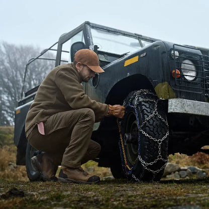 Man installing tire chains wearing Härkila Hill Trousers, perfect for country hunting gear