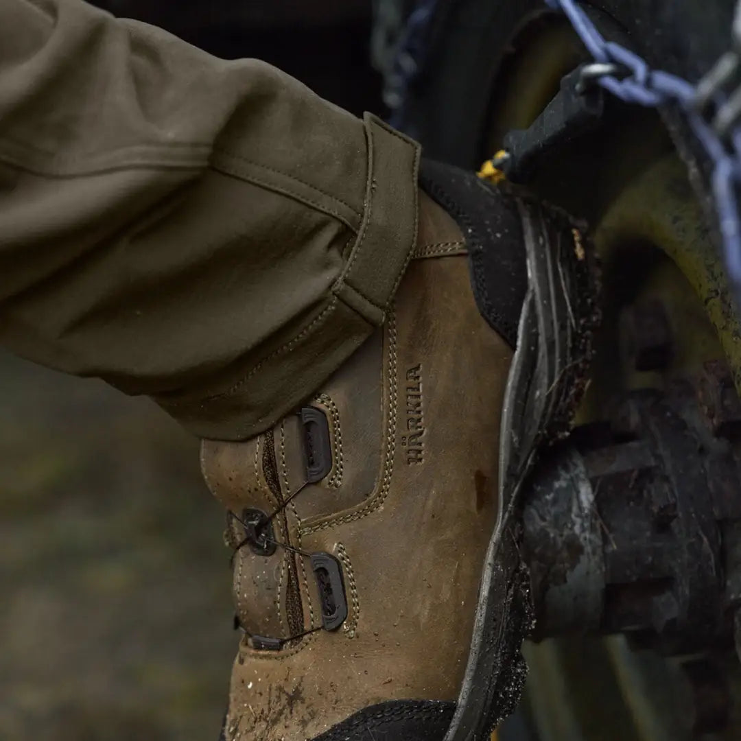 Muddy brown leather boot paired with Härkila Hill Trousers for hunting and country wear