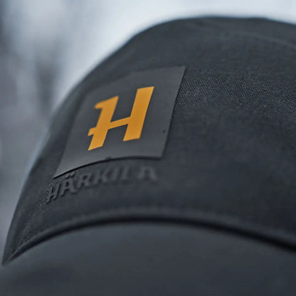 Black härkila instinct cap fabric with orange H logo for style and comfort