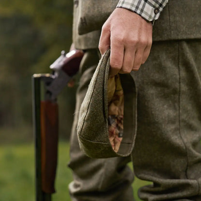 Hunter in country clothing wearing Härkila Kenmore Cl Flat Cap with shotgun for hunting