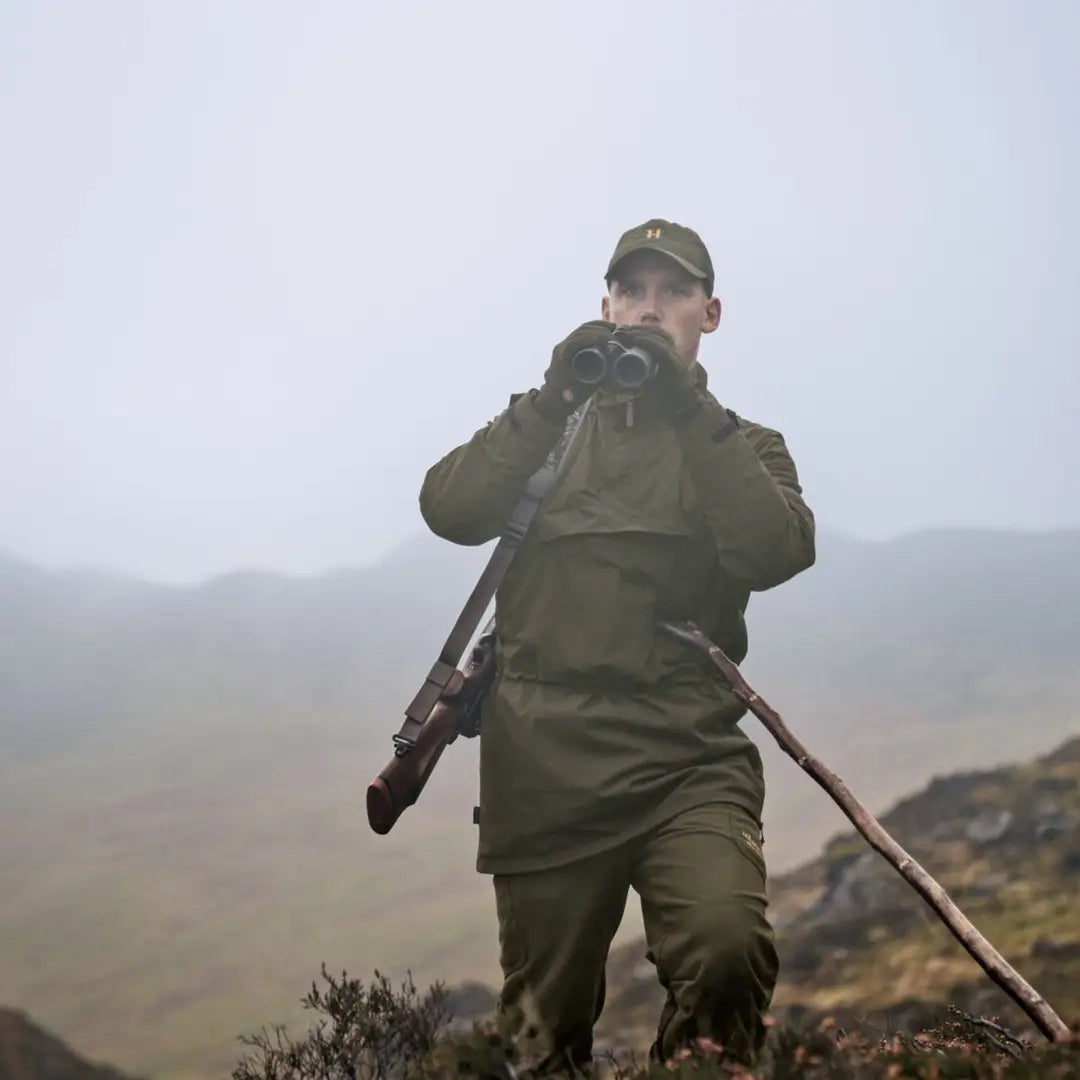 Hunter with binoculars and rifle wearing Härkila Orton Tech packable smock, ideal for country clothing
