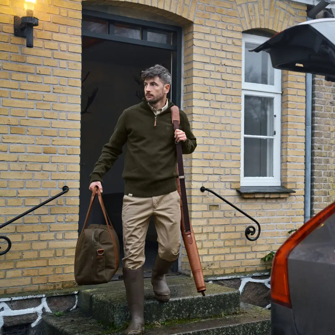 Man in hunting attire wearing Härkila Vincent Merino Half Zip Pullover for outdoor adventure