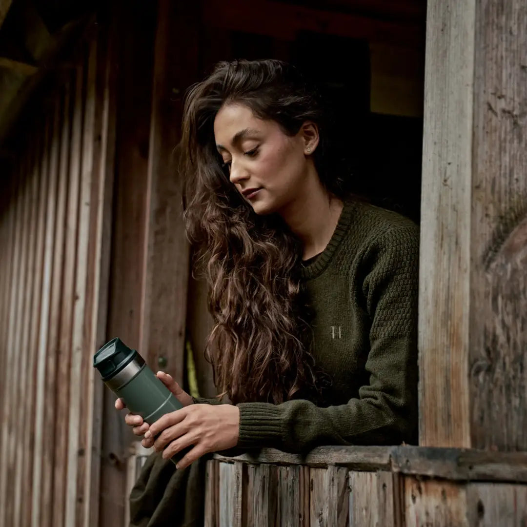 Green insulated travel mug with Härkila Vinnie Womens Merino Pullover, cozy merino pullover style