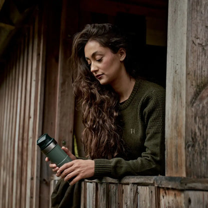 Green insulated travel mug with Härkila Vinnie Womens Merino Pullover, cozy merino pullover style