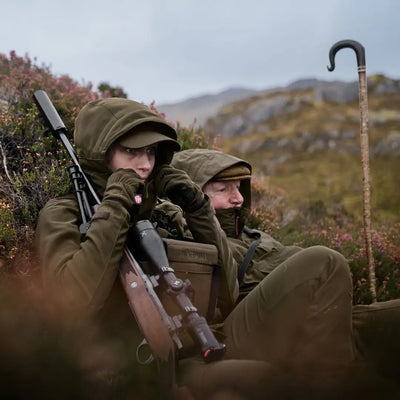 Two hunters in camo with rifle and walking stick in lush vegetation wearing Harkila Pro Hunter GTX