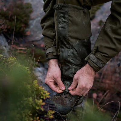 Hands tying laces of a rugged boot with Harkila Pro HWS Gaiters for outdoor adventures