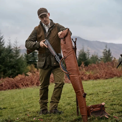 Man in Harkila Rannoch HWS shooting jacket holding a shotgun by a leather case